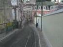 em plena pra�a dos restauradores, lisboa, est� o elevador da gl�ria, inaugurado em 24 de outubro de 1885.

faz o trajecto baixa - bairro alto.

foi constru�do pelo engenheiro portugu�s raoul mesnier du ponsard. come�ou por funcionar com dep�sitos de �gua, que, graviticamente, faziam descer um dos ascensores e subir o outro. depois foi movido a vapor e a partir de 1914, passou a mover-se a energia el�ctrica.

at� finais do s�culo xix, a ilumina��o dentro da cabine era feita com velas, durante as viagens nocturnas.

desde fevereiro de 2002, o elevador est� classificado como monumento nacional.
(wikipedia)


the gl�ria funicular was opened in 1885 and in february 2002 it was classified as a national monument. it was the second of its kind in lisbon, thanks to the initiative of the new lisbon mechanical lift company (nova companhia dos ascensores mec�nicos de lisboa - n.c.a.m.l.). this company specialised in the building and running of urban transport on sloping terrain. the first of its lifts was the lavra, opened the year before.

the story of this lift can be traced back to 1875, when the lisbon city council gave the rights to two individuals to set up a form of transport on sloping terrain in the cal�ada da gl�ria. the construction projects, however, were never approved and time slipped by.

in 1882, the subject was in the air again and the construction rights were awarded at this juncture to an engineer from porto, raoul mesnier de ponsard. he immediately transferred the rights to the n.c.a.m.l.

the carriages were different from anything that lisbon had ever seen. they had two floors, the lower one with benches along the sides, the backs towards the street and the upper one also with two benches laid out lengthwise but back to back so that the passengers looked out at the walls of the nearby buildings. access to the top floor was by spiral staircase on the platform which was at the upper end of the carriage.

traction was with rack and cable, with water as the counterweight, and the carriages were connected by a cable so that they counterbalanced each other. they had water tanks on board, which emptied when they reached the restauradores square and filled when they were at the top, in the rua da miseric�rdia. the difference in weight made the system work. close to the internal rails along the length of the route there was a rack where the cogs of the wheels fitted. these cogs were connected to the axis, allowing the brake operator to change the speed of the carriage.

each carriage had a clamp which was connected to the cable and a powerful brake which gripped the two internal wheels by means of a pad, a system which is still in use today. apart from this, there was another brake which worked by pressure on the rails. each carriage weighed about 10 tons and ran on two 25 horsepower electric engines working jointly.

the carriages could only start if both brake operators worked together but it only needed one operator to stop them. the electric current was transmitted by a pantograph on the roof. the bodywork was also different from previously. the carriages were made of wood, painted the colour of mahogany and the windows had iron bars to stop the passengers from leaning out. there were two benches placed lengthwise and between 20 and 22 passengers could be carried at any one time.

in september 1915, the cal�ada da gl�ria was electrified and came back into service

some years later, in 1926 to be precise, the n.c.a.m.l. was wound up and carris acquired the operating concession, along with all the rolling stock and fixtures. the first thing that the new owner did was to build a shelter for passengers, in restauradores square. many people voiced their disapproval of this, especially in the media, and it did not in fact last for very long. the shelter was opened on 4 november 1927 and it saw its last days in 1934.

it was also in the thirties that the carriages were painted yellow, this being the standard colour which was used by carris and still is.

http://www.carris.pt/en/index.php?area=servicos&subarea=servicos_ascensores_gloria

valpard films http://valpardfilms.awardspace.com/
