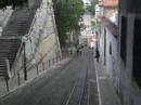 em plena pra�a dos restauradores, lisboa, est� o elevador da gl�ria, inaugurado em 24 de outubro de 1885.

faz o trajecto baixa - bairro alto.

foi constru�do pelo engenheiro portugu�s raoul mesnier du ponsard. come�ou por funcionar com dep�sitos de �gua, que, graviticamente, faziam descer um dos ascensores e subir o outro. depois foi movido a vapor e a partir de 1914, passou a mover-se a energia el�ctrica.

at� finais do s�culo xix, a ilumina��o dentro da cabine era feita com velas, durante as viagens nocturnas.

desde fevereiro de 2002, o elevador est� classificado como monumento nacional.
(wikipedia)


the gl�ria funicular was opened in 1885 and in february 2002 it was classified as a national monument. it was the second of its kind in lisbon, thanks to the initiative of the new lisbon mechanical lift company (nova companhia dos ascensores mec�nicos de lisboa - n.c.a.m.l.). this company specialised in the building and running of urban transport on sloping terrain. the first of its lifts was the lavra, opened the year before.

the story of this lift can be traced back to 1875, when the lisbon city council gave the rights to two individuals to set up a form of transport on sloping terrain in the cal�ada da gl�ria. the construction projects, however, were never approved and time slipped by.

in 1882, the subject was in the air again and the construction rights were awarded at this juncture to an engineer from porto, raoul mesnier de ponsard. he immediately transferred the rights to the n.c.a.m.l.

the carriages were different from anything that lisbon had ever seen. they had two floors, the lower one with benches along the sides, the backs towards the street and the upper one also with two benches laid out lengthwise but back to back so that the passengers looked out at the walls of the nearby buildings. access to the top floor was by spiral staircase on the platform which was at the upper end of the carriage.

traction was with rack and cable, with water as the counterweight, and the carriages were connected by a cable so that they counterbalanced each other. they had water tanks on board, which emptied when they reached the restauradores square and filled when they were at the top, in the rua da miseric�rdia. the difference in weight made the system work. close to the internal rails along the length of the route there was a rack where the cogs of the wheels fitted. these cogs were connected to the axis, allowing the brake operator to change the speed of the carriage.

each carriage had a clamp which was connected to the cable and a powerful brake which gripped the two internal wheels by means of a pad, a system which is still in use today. apart from this, there was another brake which worked by pressure on the rails. each carriage weighed about 10 tons and ran on two 25 horsepower electric engines working jointly.

the carriages could only start if both brake operators worked together but it only needed one operator to stop them. the electric current was transmitted by a pantograph on the roof. the bodywork was also different from previously. the carriages were made of wood, painted the colour of mahogany and the windows had iron bars to stop the passengers from leaning out. there were two benches placed lengthwise and between 20 and 22 passengers could be carried at any one time.

in september 1915, the cal�ada da gl�ria was electrified and came back into service

some years later, in 1926 to be precise, the n.c.a.m.l. was wound up and carris acquired the operating concession, along with all the rolling stock and fixtures. the first thing that the new owner did was to build a shelter for passengers, in restauradores square. many people voiced their disapproval of this, especially in the media, and it did not in fact last for very long. the shelter was opened on 4 november 1927 and it saw its last days in 1934.

it was also in the thirties that the carriages were painted yellow, this being the standard colour which was used by carris and still is.

http://www.carris.pt/en/index.php?area=servicos&subarea=servicos_ascensores_gloria

valpard films http://valpardfilms.awardspace.com/