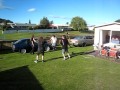 Four grown men jump through a hula hoop
