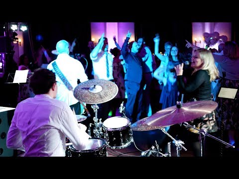 Hochzeitsband NRW mit Sängerin, Gitarrist und Schlagzeuger bei Live Auftritt auf einer Hochzeitsfeier mit tanzenden und feiernden Gästen
