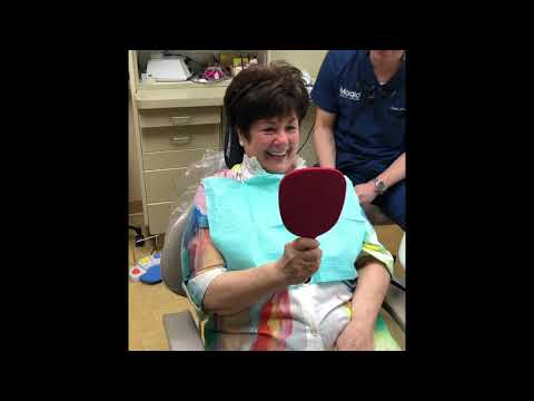 Dental patient admiring her new smile in red mirror