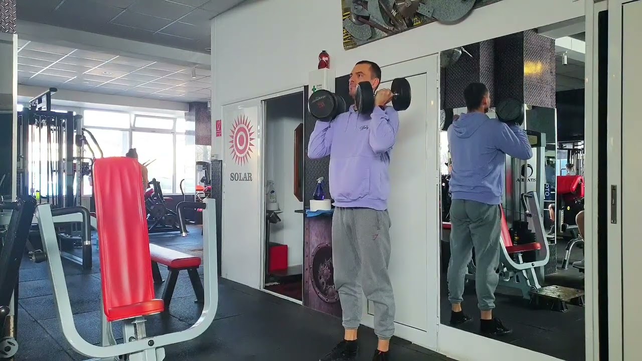 Genuflexiuni cu două gantere ținute la umeri