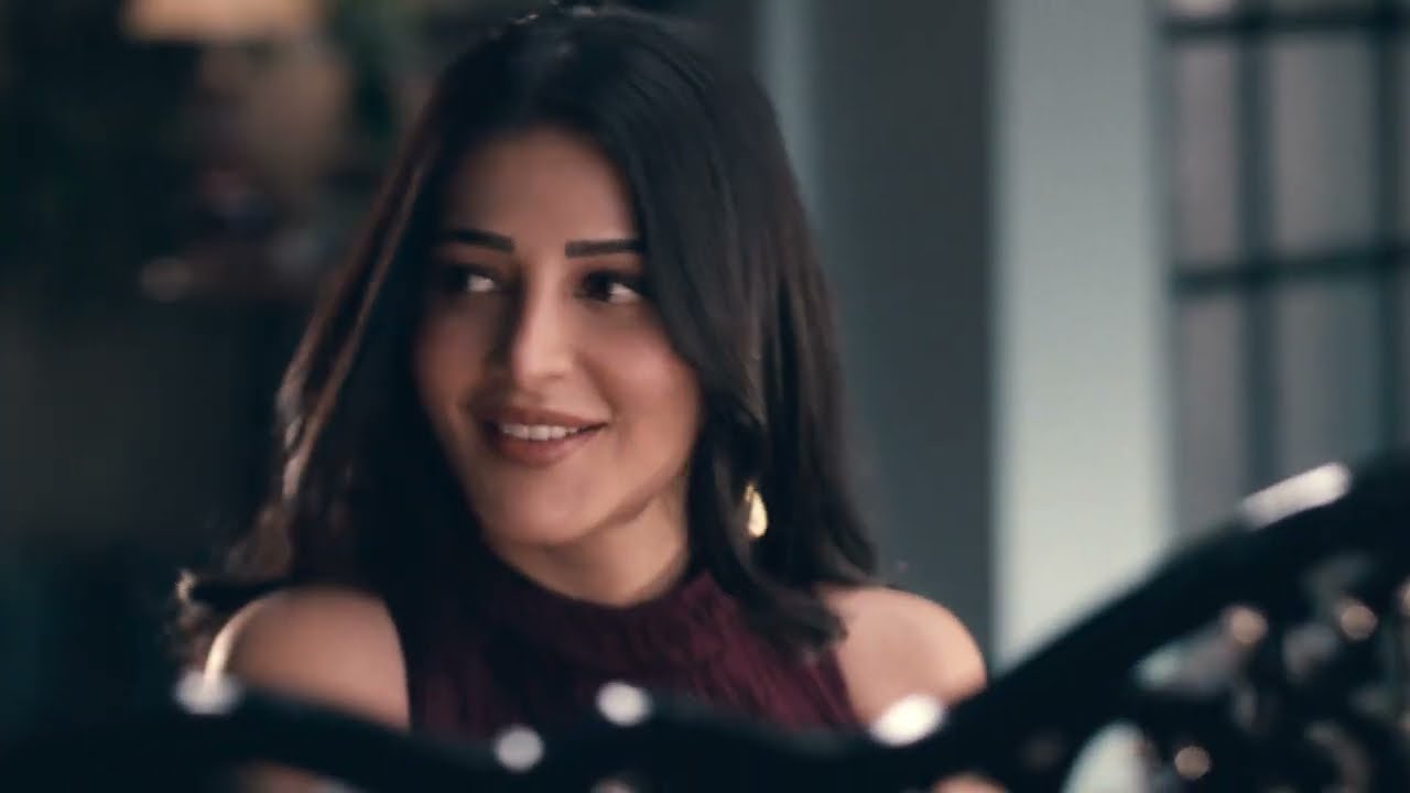 A woman in a dark maroon top smiles softly in a dimly lit blue-toned room