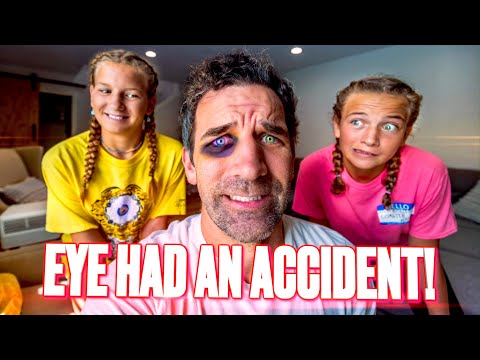 Center-close photo of a man with a bruised eye and purple makeup around it, flanked by two smiling girls in yellow and pink shirts, in a living room; bold caption 'EYE HAD AN ACCIDENT!' across the bottom.