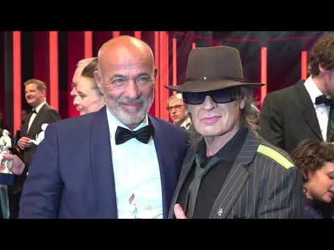 Udo Lindenberg übergibt mit Küsschen an Lindenberg-Darsteller Jan Büllow den Bayerischen Filmpreis