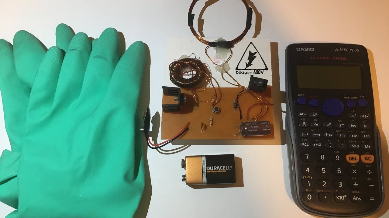 EMP generator circuit on a custom PCB beside a calculator