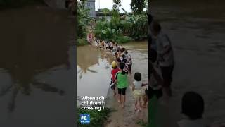 Elders line up to help children cross river on their way home