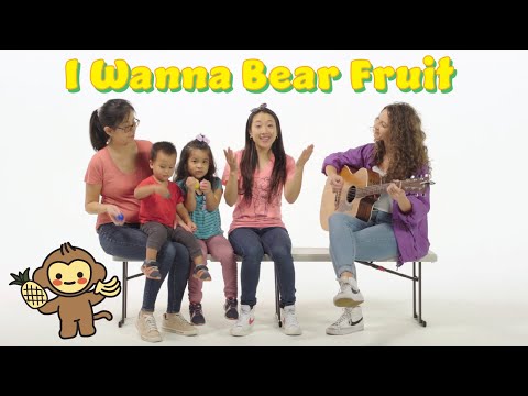 Group of people sitting on a bench: a guitar teacher or performer on the right, singing, with children and a woman, bright text 'I Wanna Bear Fruit' above.