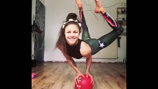 A girl puts glasses on with legs while standing on a ball with hands