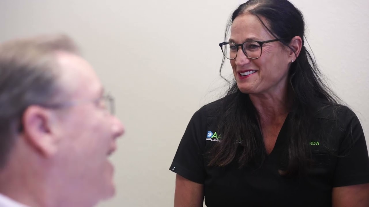 Man in dental chair talking to dental team member