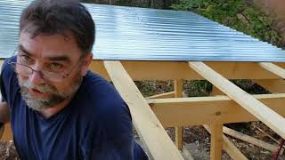 Installing metal corrugated roofing on the goat barn.