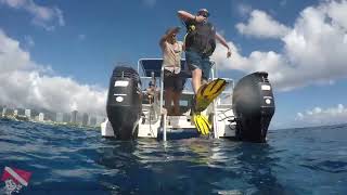 First-time scuba diver doing a back-roll entry into the water near Honolulu, Oahu