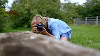 woman using a Canon camera to photograph a tree trunk lying on the ground