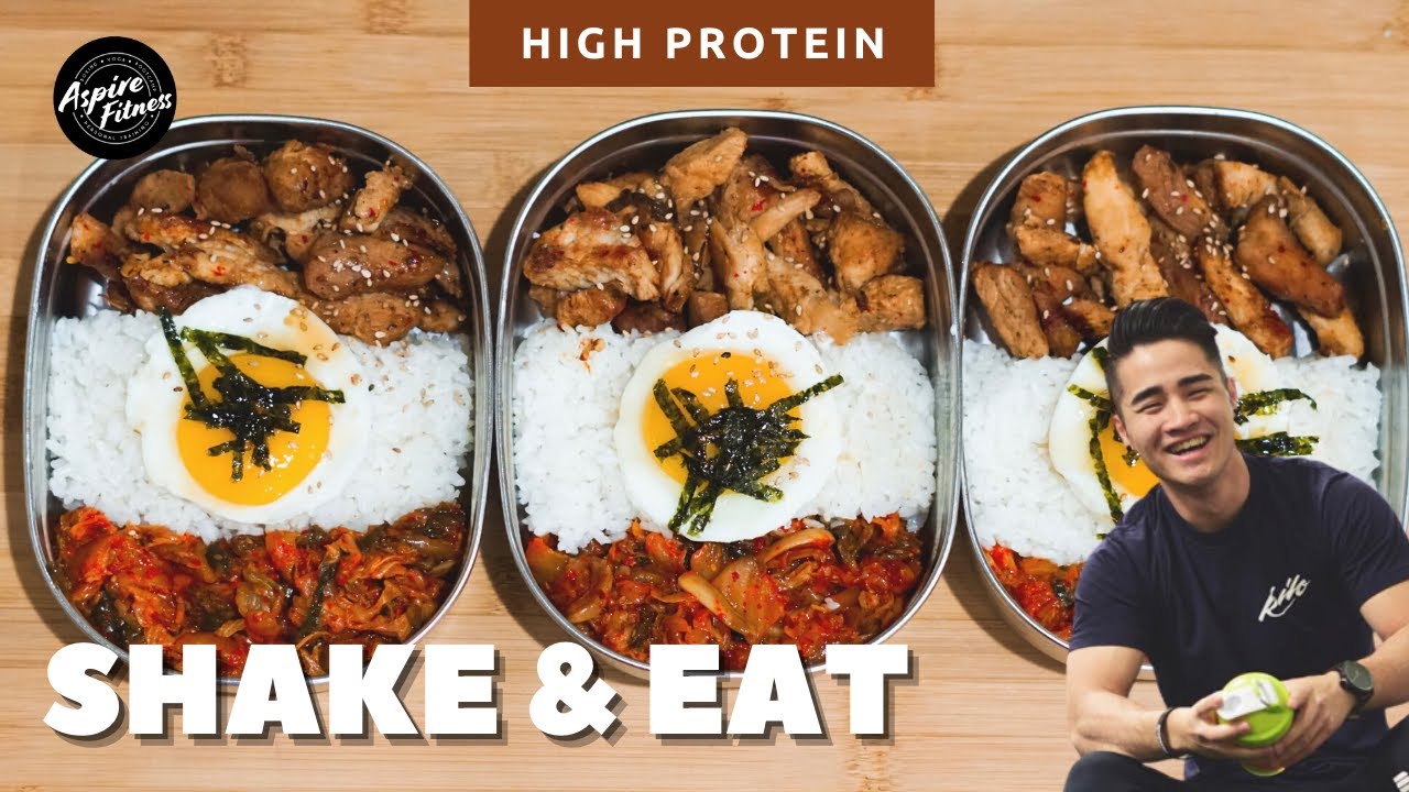 A retro Korean tin dosirak lunchbox being shaken with rice kimchi and toppings inside ready to mix into a bibimbap style meal