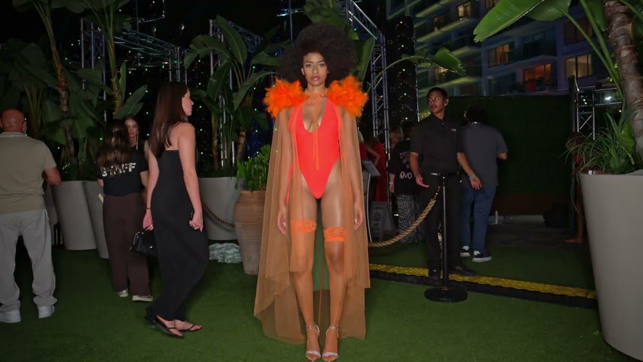 Model Infante poses at Miami Swim Week The Shows wearing orange piece with sheer cape