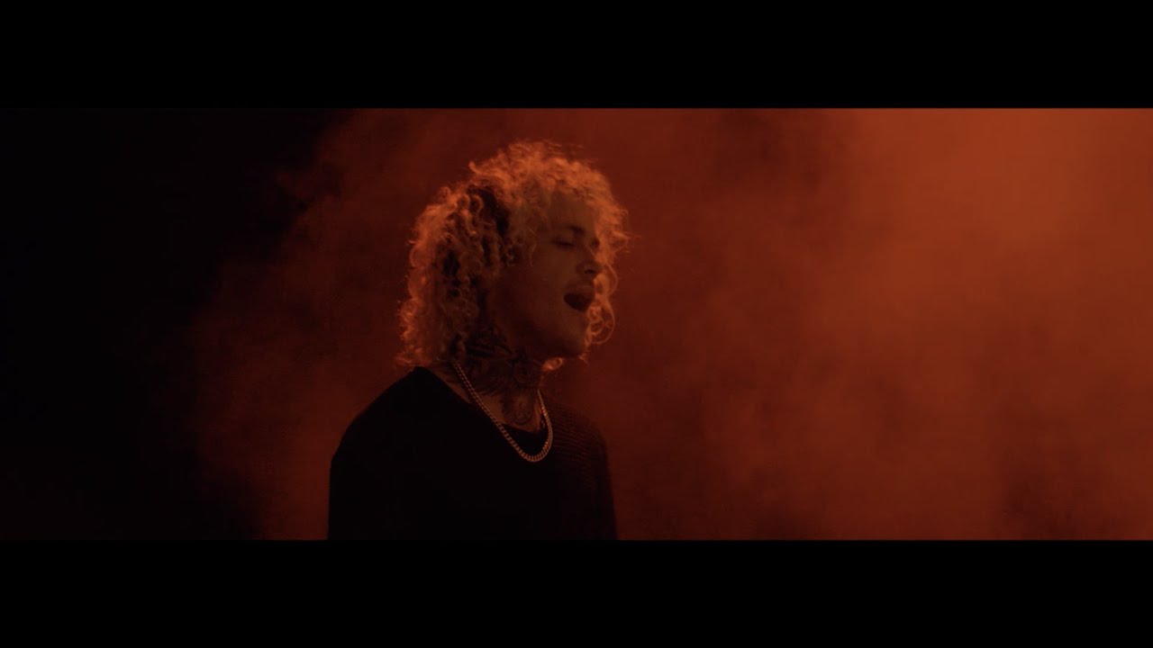 Singer lit by orange smoke in the music video for After Ours by Dahl