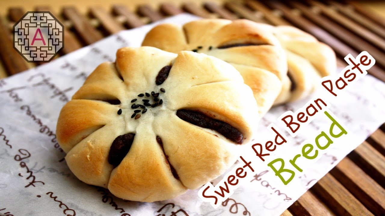 A fresh baked Korean danpatbbang sweet red bean bread bun cut open showing the dark red sweet bean paste filling inside the golden brown shell