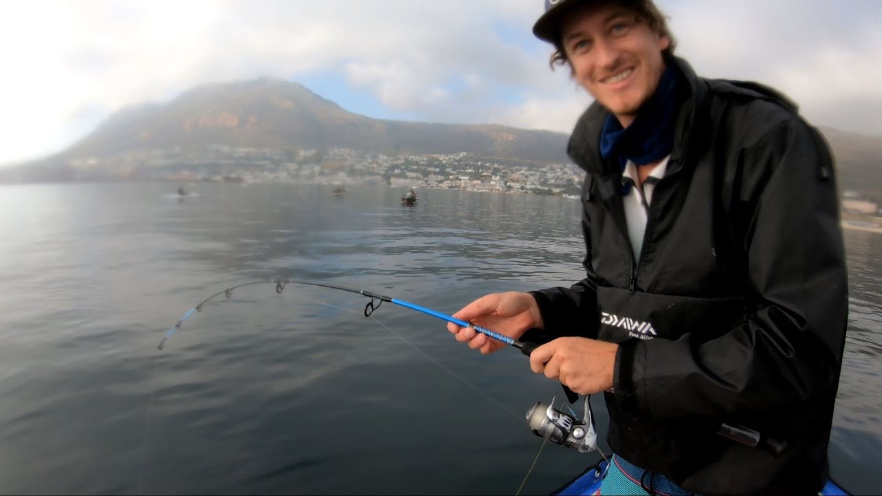 Grinning man with bent fishing rod in the water