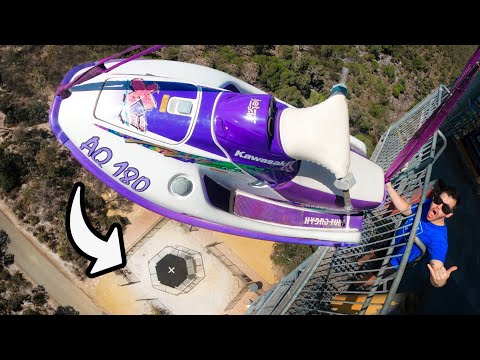Thrill ride scene: a purple Kawasaki jet ski is mounted above a platform while a man in blue stands on the railing, giving a thumbs-up.