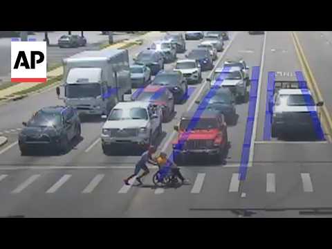 Video Thumbnail: Man dressed as Spider-Man helps a person in a wheelchair cross the road