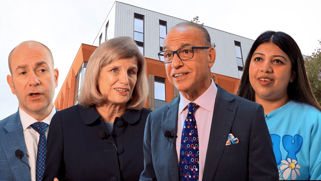 Four people standing in front of The Cavendish Building, apparently mid conversation, with lapel mics clipped to them. 