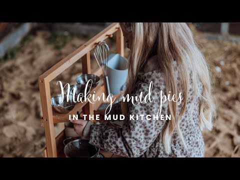 Little girl is making mud pies in her outdoor play kitchen