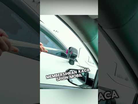 Dia membersihkan kaca spion mobil asing