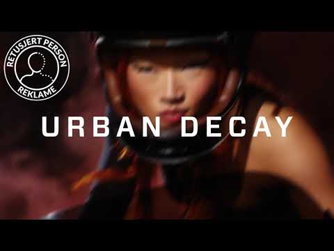 Urban Decay All Nighter setting spray i svart flaske med lilla spraypumpe mot lilla bakgrunn. Teksten “URBAN DECAY”, “NEW all nighter setting spray” og “UP TO 24 HOURS HOLD” vises i videoen.
