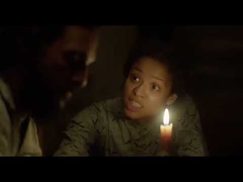 Trailer beat: town square faces the camera as restrained strings underline the scene