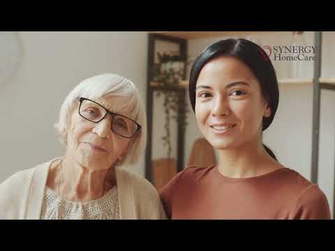 Senior woman in wheelchair enjoying time in the park with caregiver