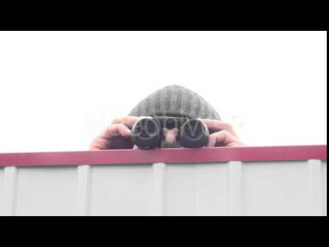 Man With Binoculars Over the Fence