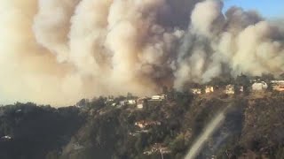 LA fire department helicopter navigates smoke over burning homes