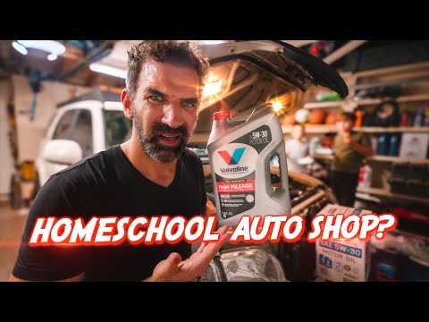 Man in a garage holding a bottle of Valvoline motor oil next to a car, with a bold red 'HOMESCHOOL AUTO SHOP?' overlay in the foreground.