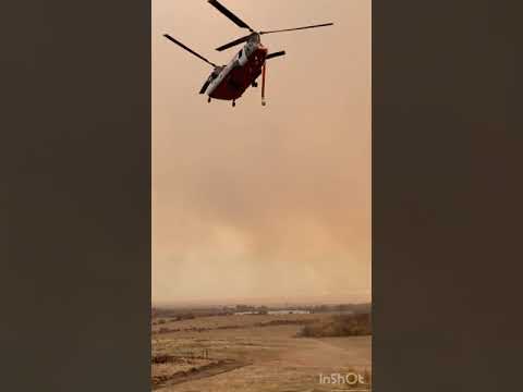 Chinook firefighting helicopter dropping water on some extreme fire behavior