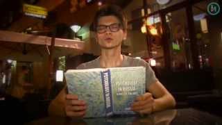 A student with glasses sitting at a desk and reading from a notebook.