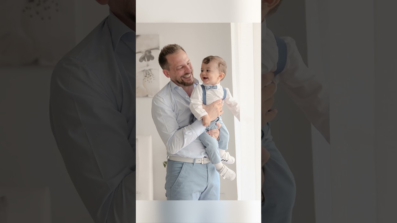 Papà e bimbo in abiti bianchi e celesti colti in un abbraccio spontaneo, fotografo Novara.