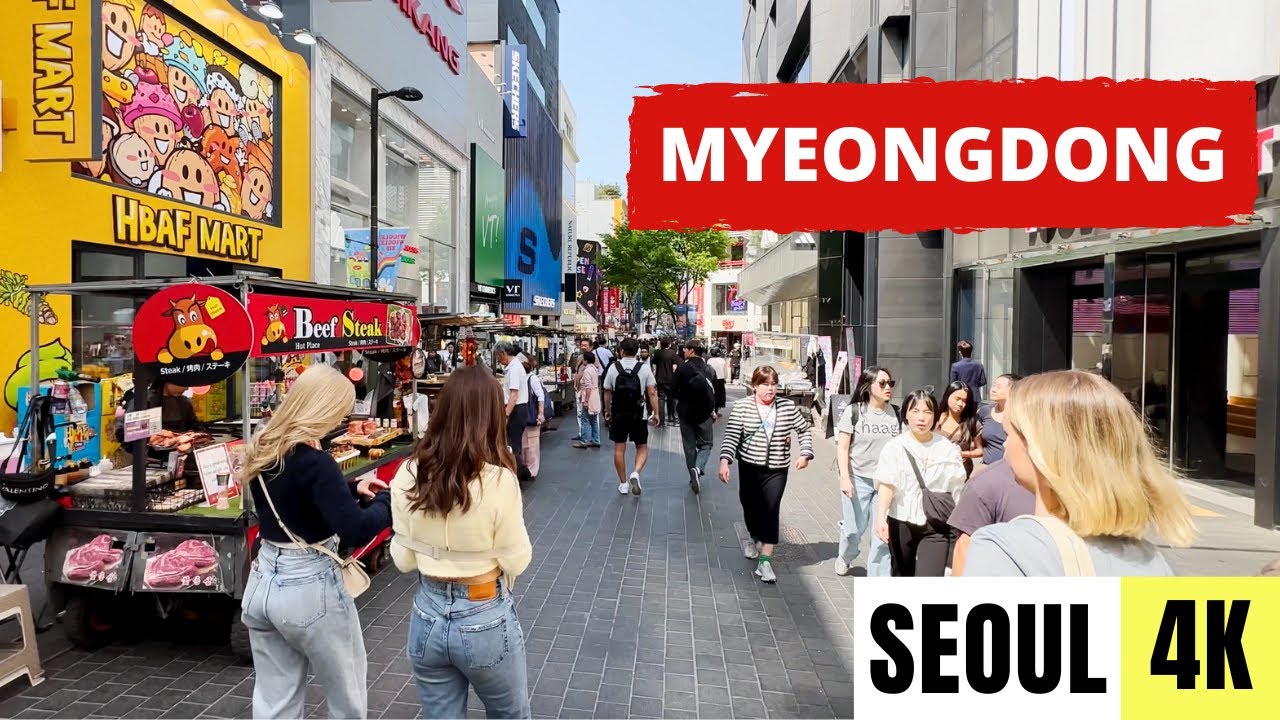 A wide view of Myeongdong shopping street in Seoul packed with tourists fashion stores K-beauty shops and street food carts during the day
