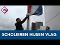 Geslaagde Haagse scholieren hijsen vlag op het winderig dak van het stadhuis