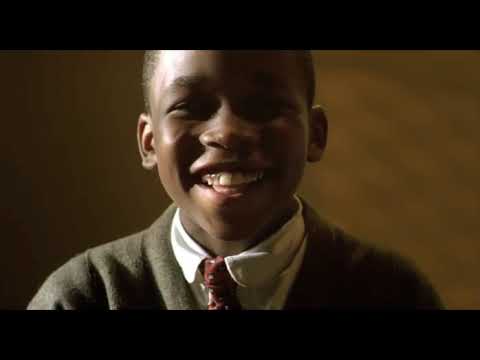Trailer still: Rooster in a white tux, mic up; Percival at the piano, eyes down—split by spotlight