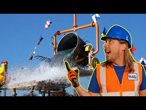 Construction worker in an orange safety vest and blue helmet points at a water splash from a slide or pipe structure behind him.