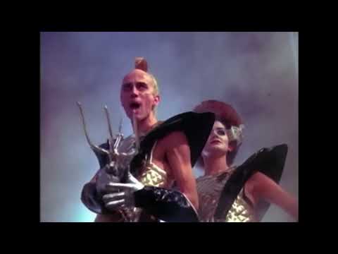 Trailer still: Frank-N-Furter at the footlights, sequins catching every spotlight