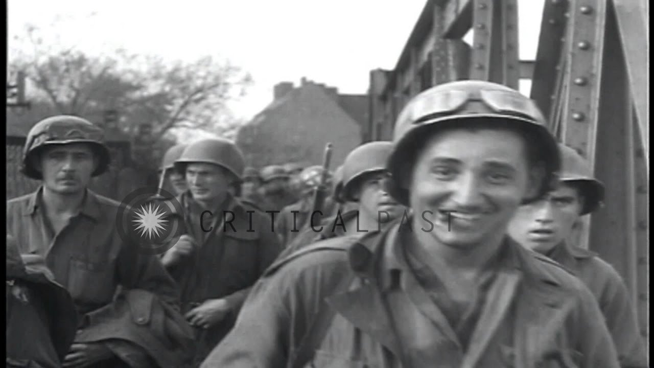Infantrymen and trucks of US 65th Division cross a bridge and drive in outskirts ...HD Stock Footage