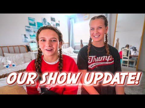 Two girls with braided hair sit in a bright bedroom, smiling at the camera with the bold 'OUR SHOW UPDATE!' text overlaid across the bottom area.