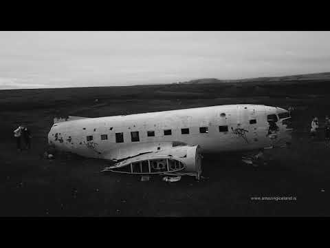 Black-and-white photograph of the wrecked DC-3 plane fuselage resting on the black sand of Sólheimasandur, Iceland.