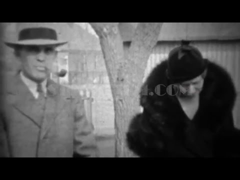 1933: Man smoking pipe wife in black fur coat with funny formal hats. DENVER, COLORADO