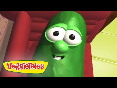 Smiling green cucumber character from VeggieTales with big eyes, inside a colorful set.
