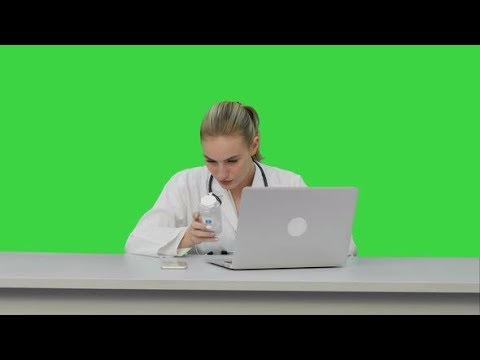 Portrait of a Nurse Studing New Pills Using Laptop Computer on a Green Screen, Chroma Key. | Stock