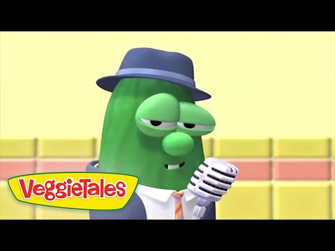 Green cucumber character in a hat and suit sings into a vintage microphone on a stage, with the VeggieTales logo in the corner.