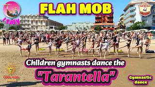 FLAH MOB. Children gymnasts dance the «Tarantella» on the beach.
