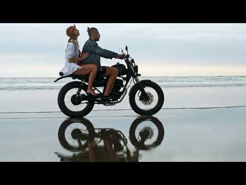couple riding a motorcycle in the beach
